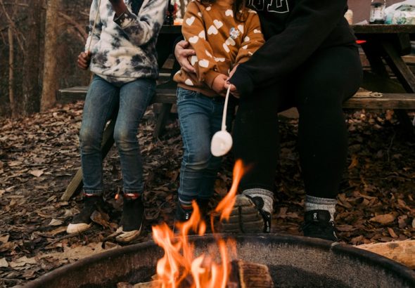 a woman and two children cooking on a grill